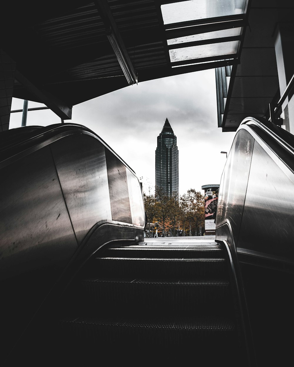 grey and black escalator with view of high-rise building