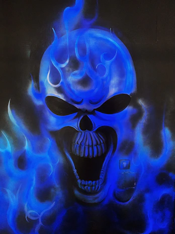 Close-up of a skull emblem with red flames on a black leather vest, highlighted against a dark background.