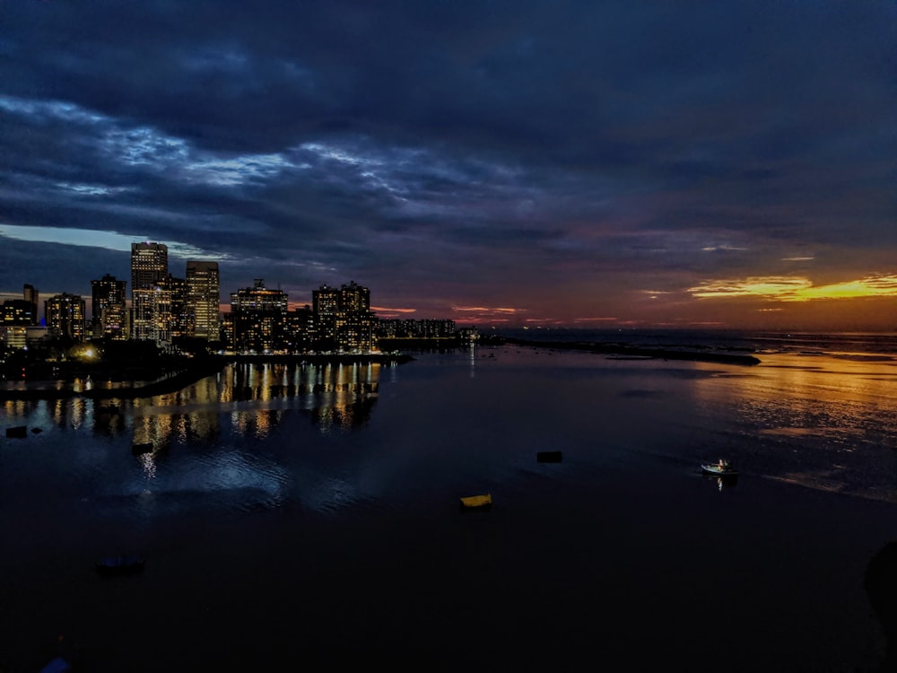 body of water near buildings at night