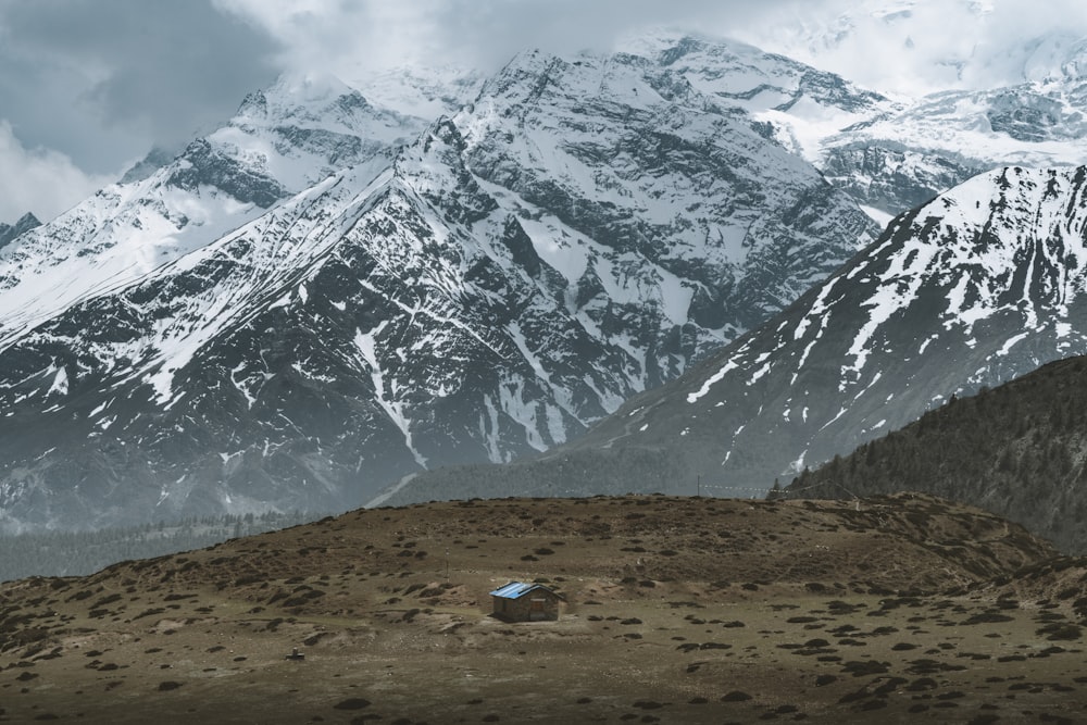 brown barn near snow-covered mountains