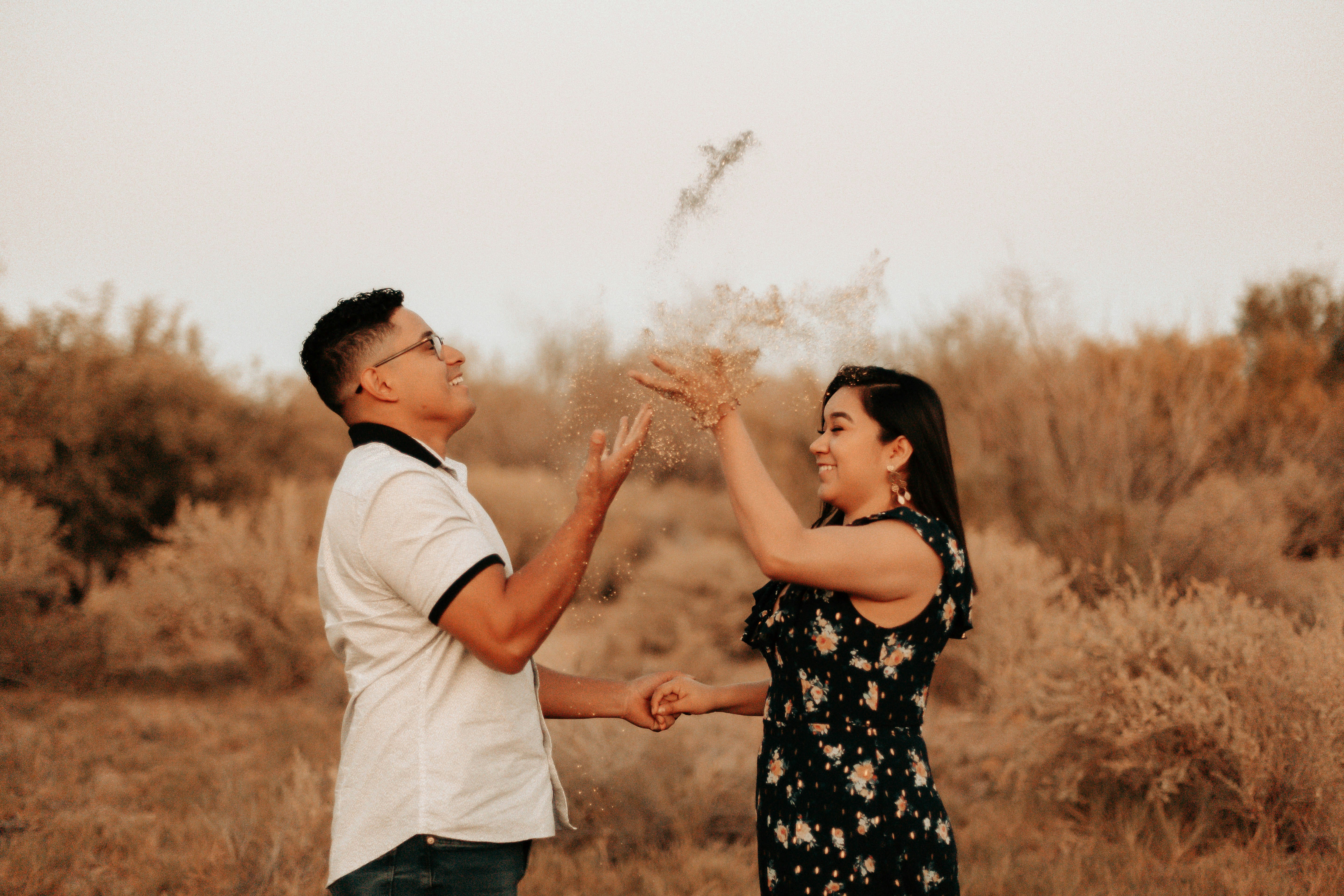 man and woman standing beside grass field