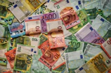Colorful euro banknotes spread out with a globe softly blurred in the background