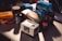 A collection of vintage film photography equipment including various boxes and rolls of film, an Olympus film camera, and film canisters. The brands visible include Kodak, Fujicolor, Ilford, and CineStill, and they are placed on a table with subdued lighting.