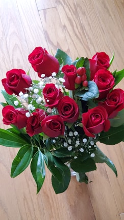 Elegant bouquet of deep red roses with classic green leaves on a wooden table