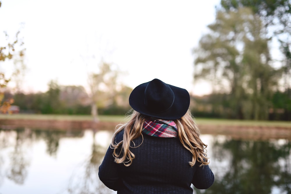 woman wearing black hat standing in front of body of water