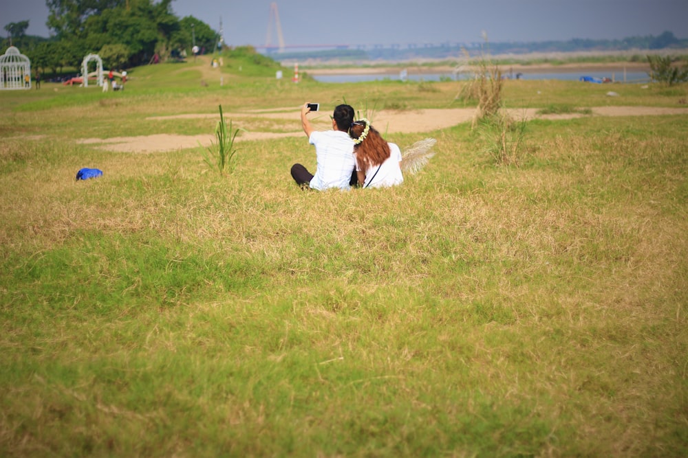 man and woman sitting on field