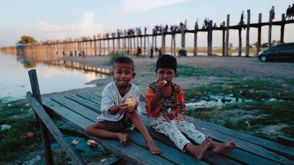 two boys sitting on brown wooden surface