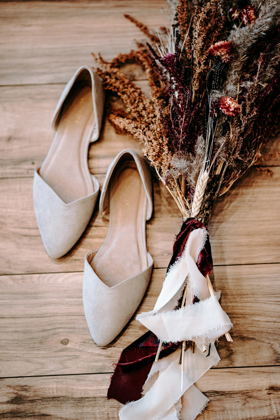 pair of shoes beside flowers