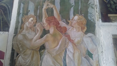 A circle of women in flowing dresses moving gracefully in nature.