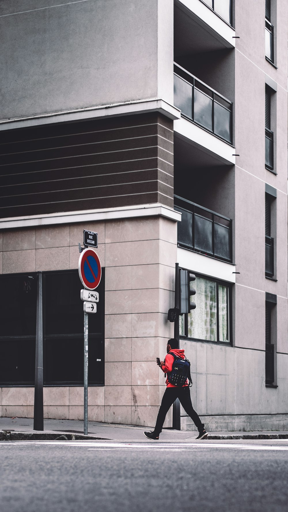 man walking on sidewalk beside signboard and building