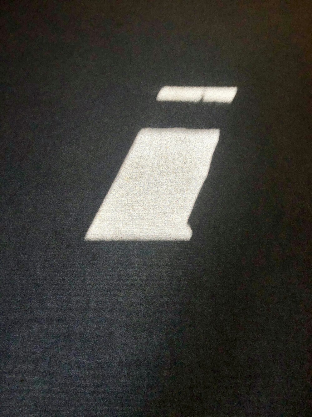 a shadow of a bed on a black floor