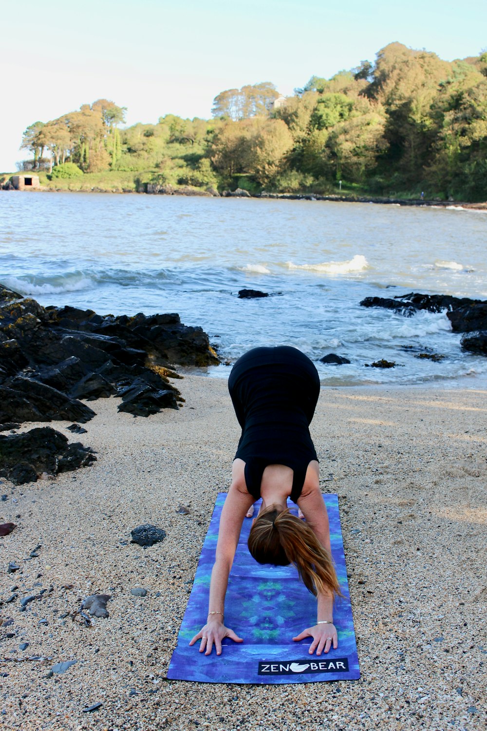 woman in black outfit doing yoga beside body of water