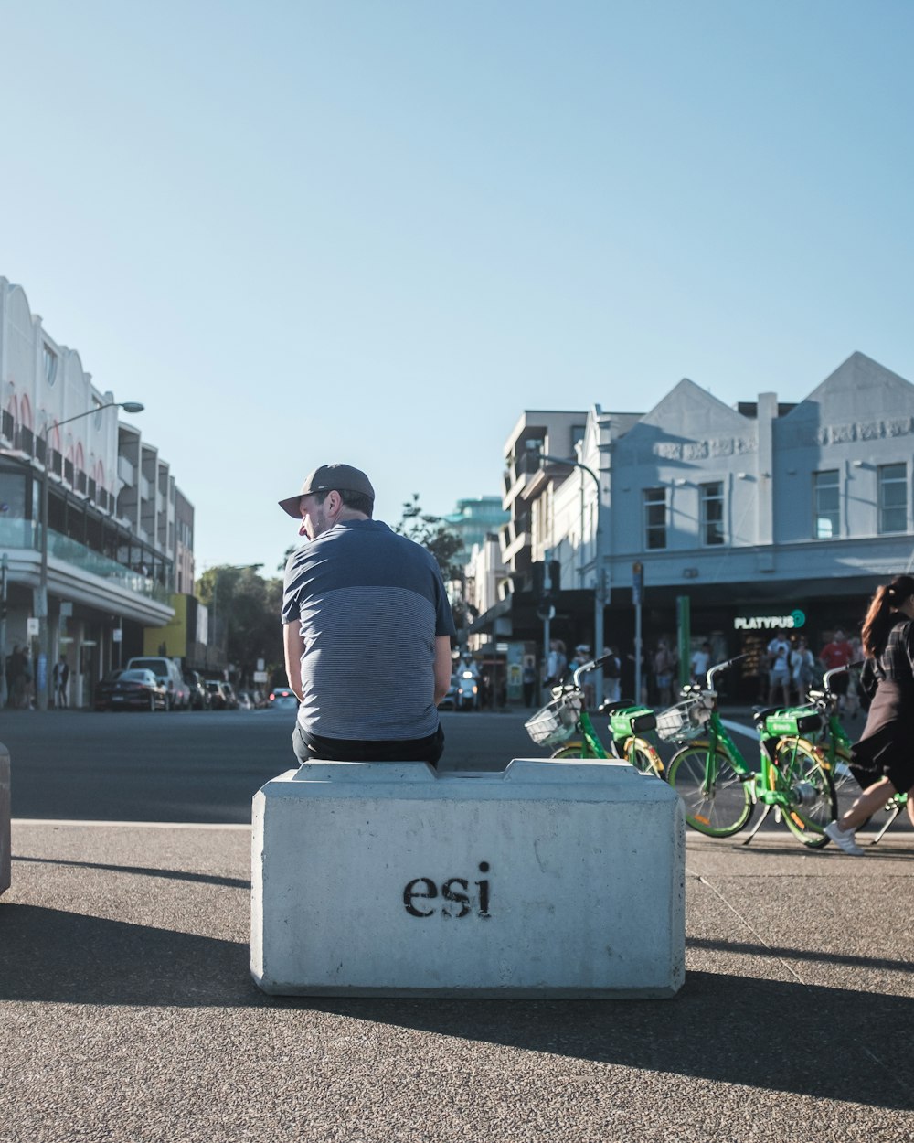 man sitting on white bench near bicycle