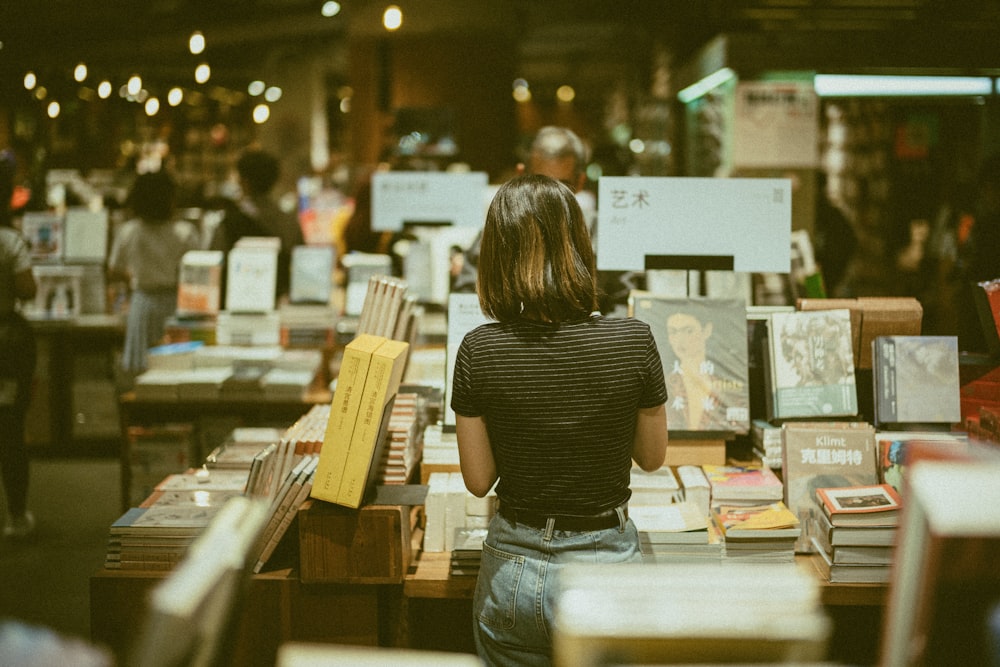 woman wearing black and gray striped shirt standing and choosing book