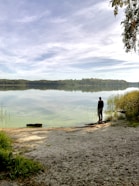 man standing front of lake during daytime