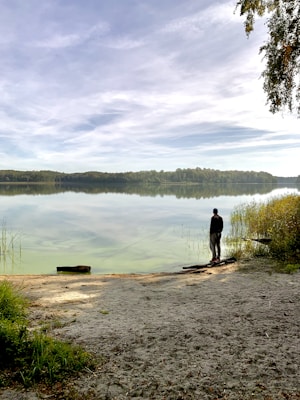 man standing front of lake during daytime