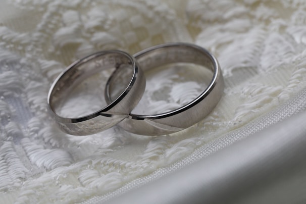 Close-up of wedding rings resting on a delicate lace fabric