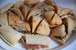 Bright and appetizing display of assorted sandwiches and snacks on a rustic tray.