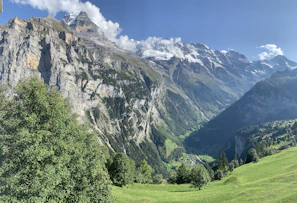 A panoramic view of the lush Fairy Meadows with towering Nanga Parbat peaks in the background.