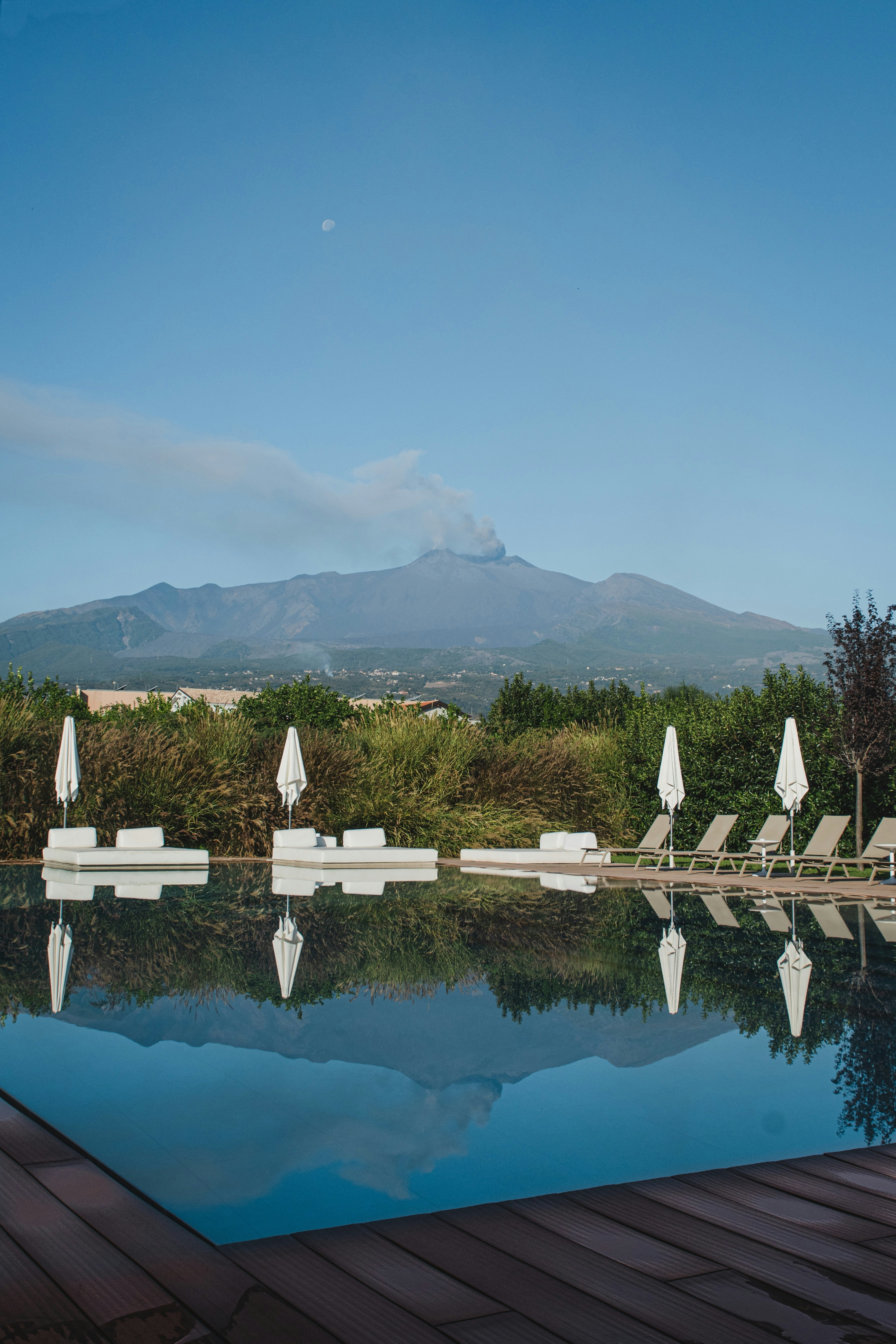 chaises longues et parasols au bord de la piscine avec bordure en bois marron