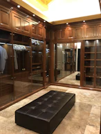 An elegant walk-in wardrobe featuring dark wood finishes and subtle lighting highlighting the craftsmanship.