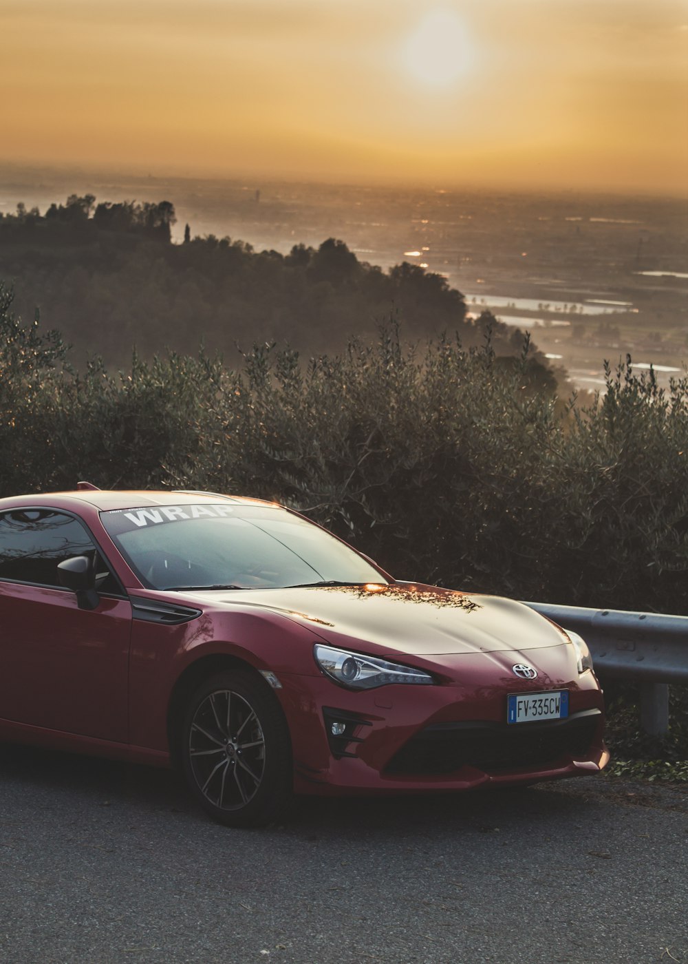 red Toyota vehicle parked on road near trees during dawn