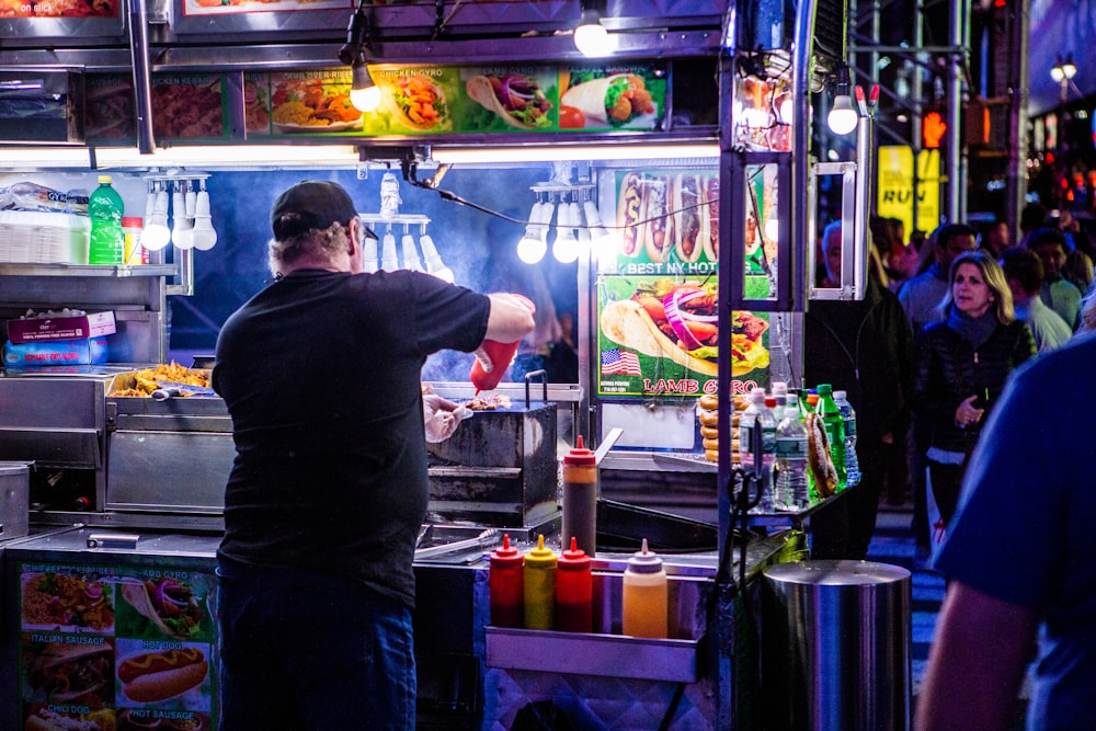 man in black shirt pouring sauce on food