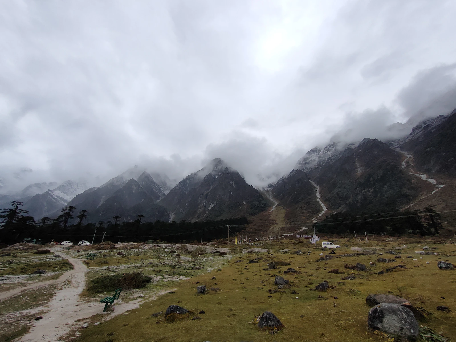 Cloud down on the snow peaks above the Yumthang valley, the meadow and a dirt track in the foreground