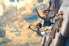 Two animated characters, a young girl and a boy, are flying through a cloudy sky in a whimsical setting. They are dressed in light blue clothes and appear joyful as they soar among fluffy clouds. The sky is vibrant, filled with a mix of bright yellow and soft blue colors, creating a playful and adventurous atmosphere. Large letters can be seen partially in the background, suggesting they are part of a sign or structure.