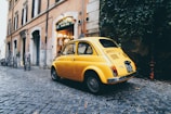 yellow 3-door hatchback parked outside a building