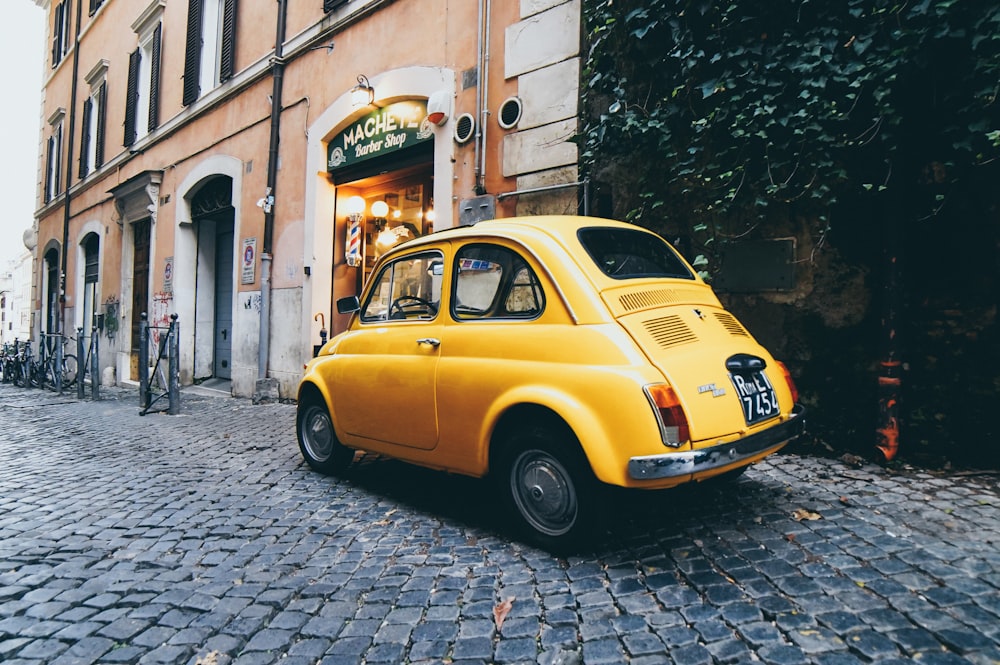 yellow 3-door hatchback parked outside a building