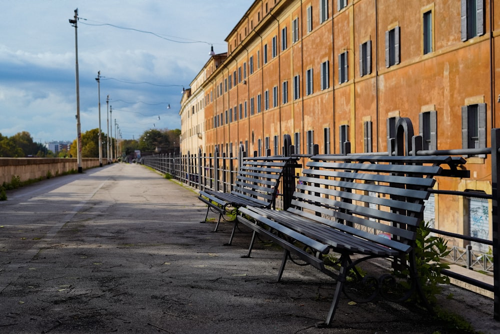 two empty benches beside railing near building