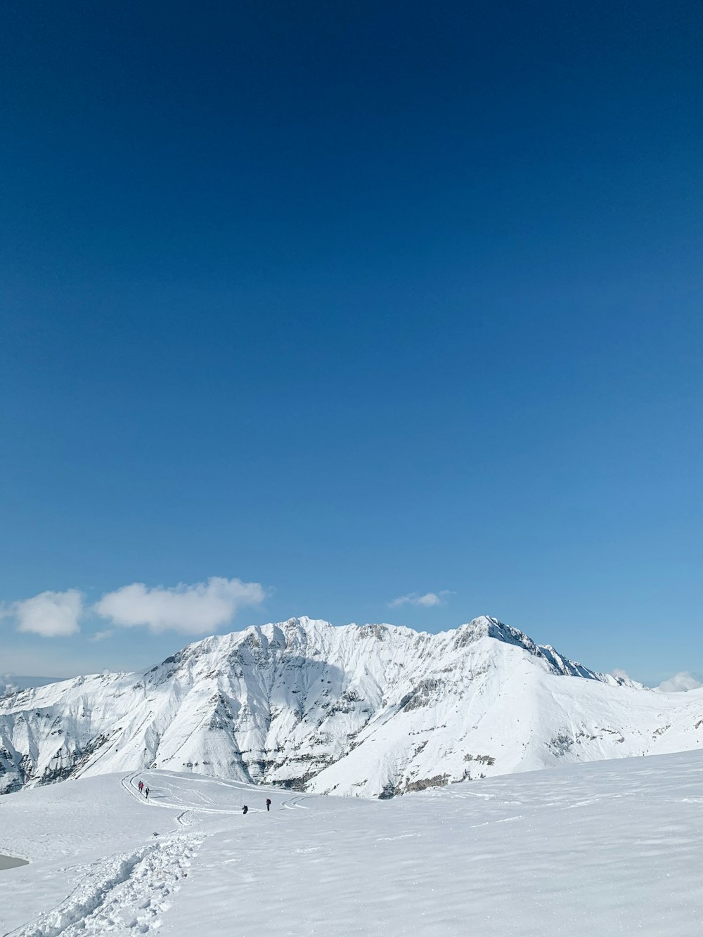 Gente de pie en el campo nevado y la montaña bajo el cielo azul y blanco durante el día