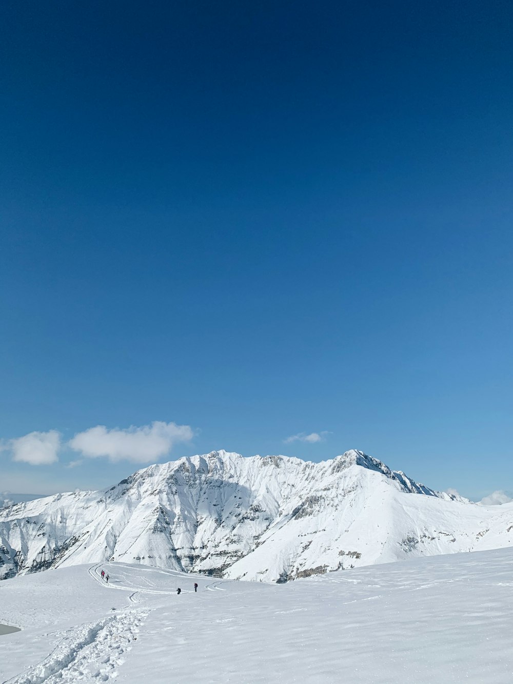 personnes debout sur le champ enneigé et la montagne sous le ciel bleu et blanc pendant la journée