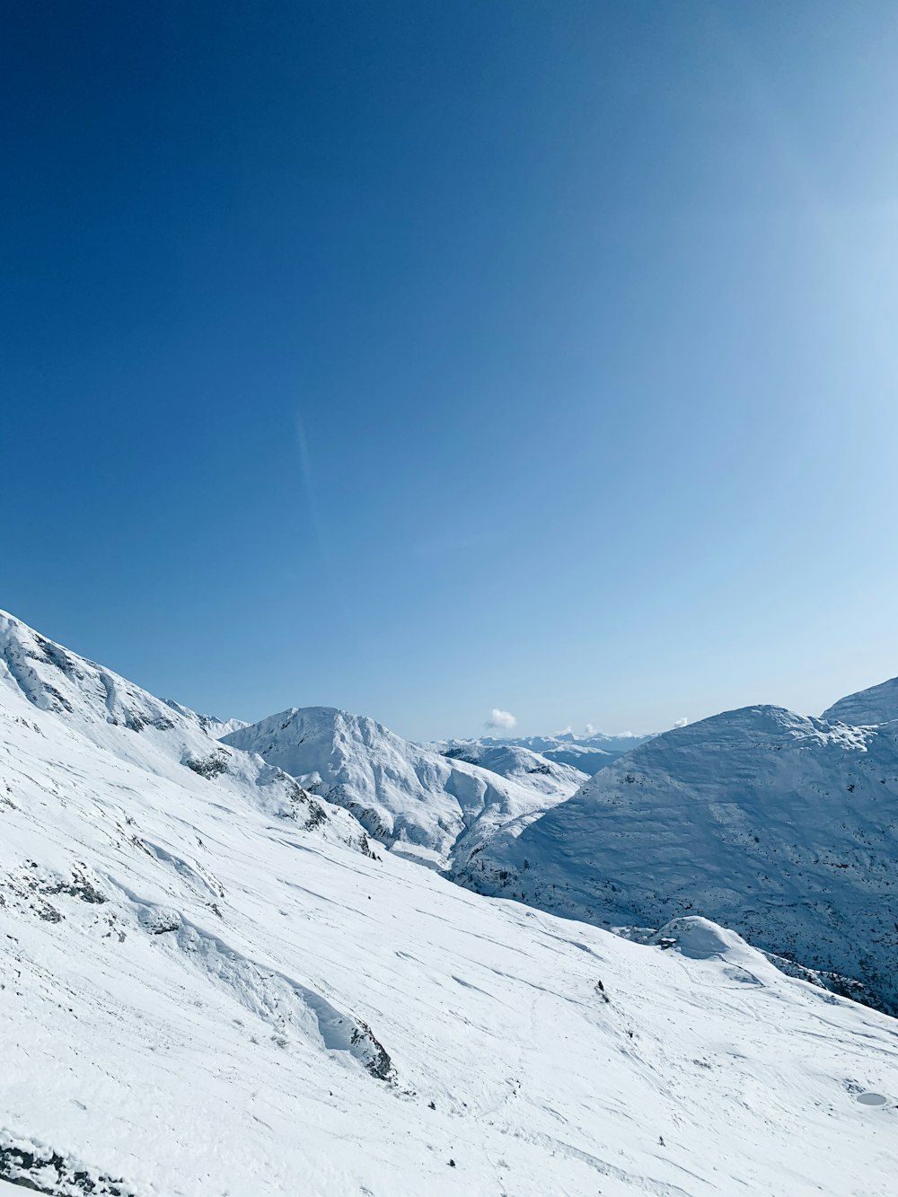 field covered with snow viewing mountain under white and blue sky during daytime