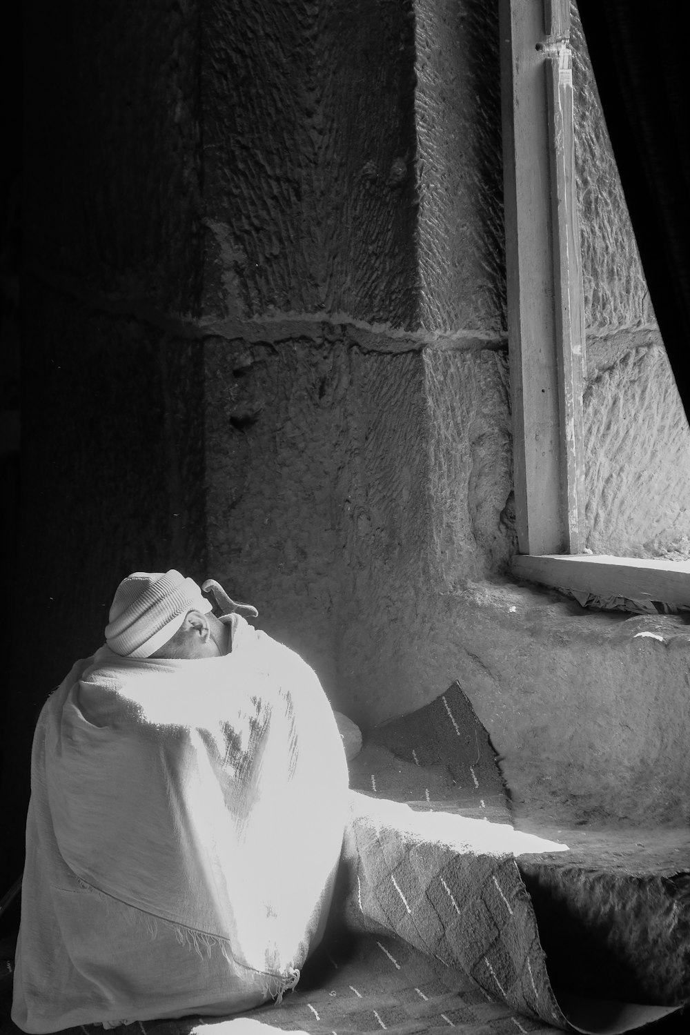 grayscale photography of man sitting while hiding face