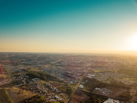 A wide aerial view of the open plots with clear roads and greenery under a bright sky.