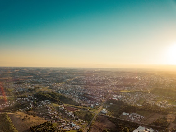 Aerial view of green land plots with city skyline in the background under a clear sky.