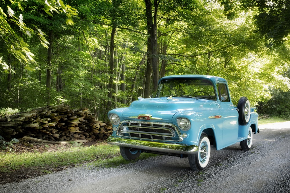 classic blue single cab pickup truck parked beside trees