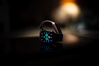 A close-up of a smart watch glowing softly on a wooden table.