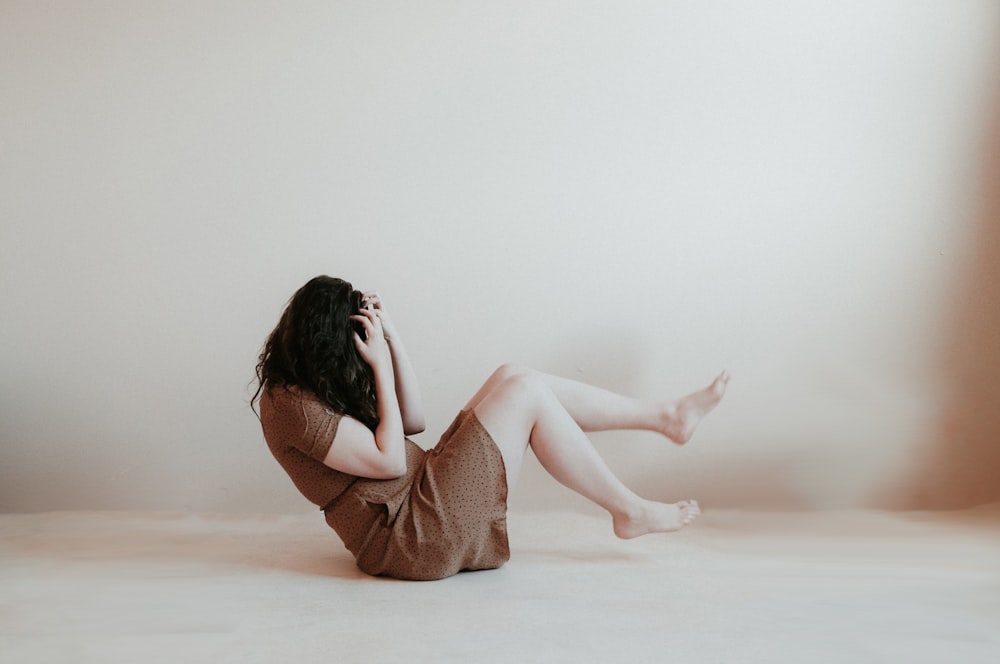 femme assise sur le sol portant une robe marron