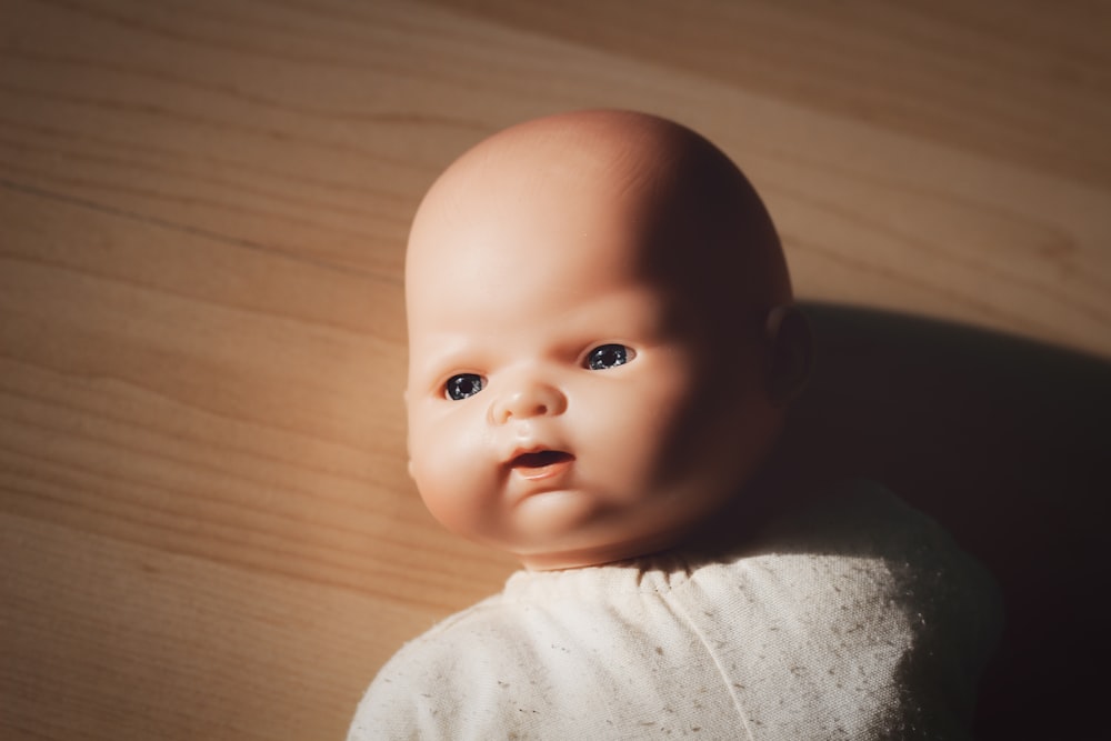 white dressed baby doll on wooden surface