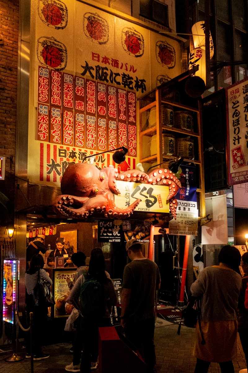 Calle comercial cubierta en Osaka con luces de neón y puestos de comida