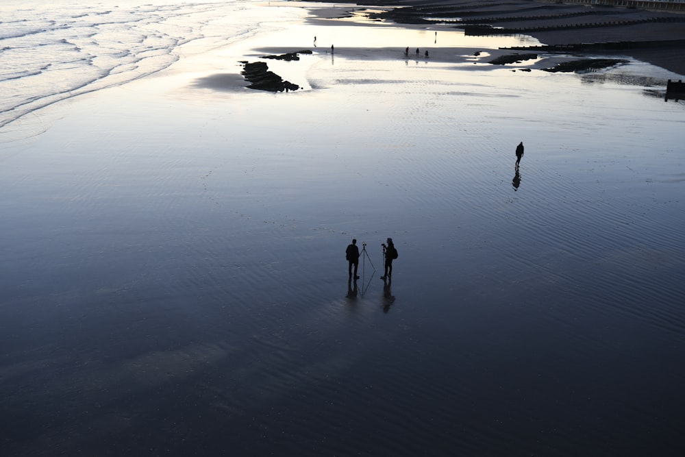 three person standing on seashore
