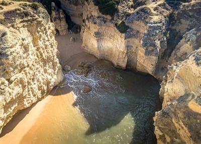 A hidden beach cove with crystal-clear water and rocky cliffs bathed in golden sunlight.
