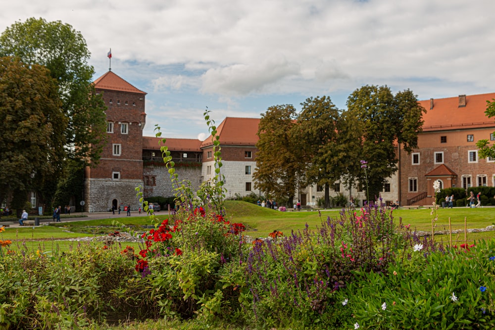 people walking near brown house with garden under white and blue sky during daytime