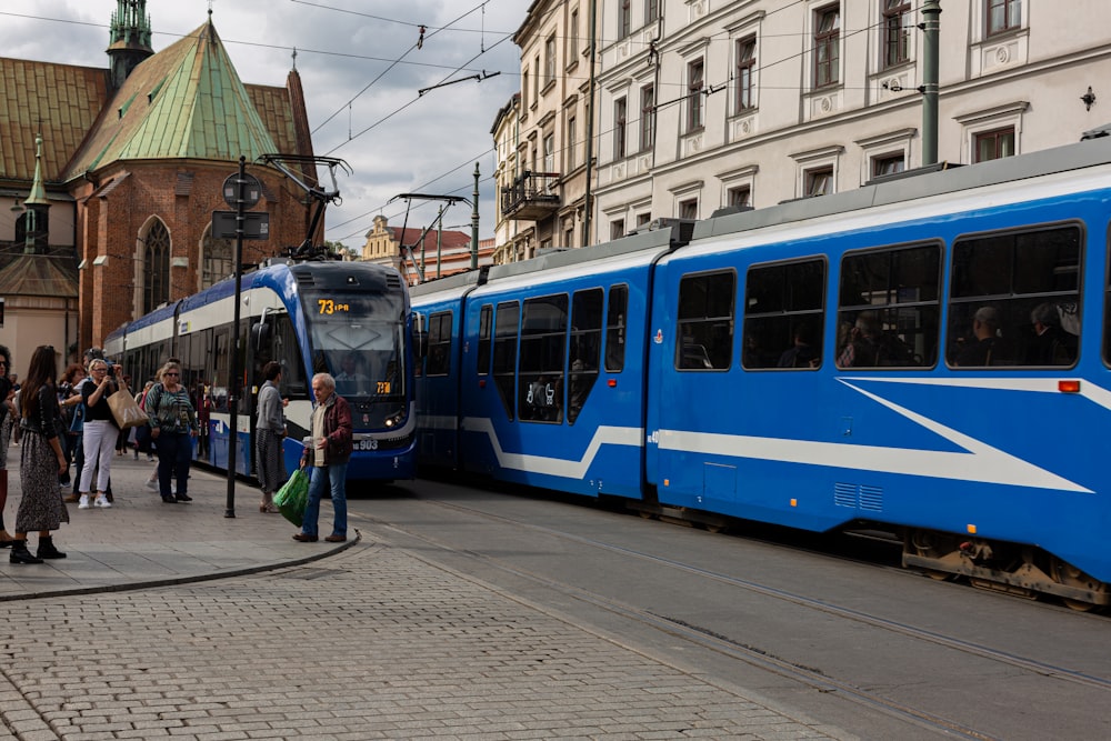 people walking near blue and white train under white and blue sky during daytime