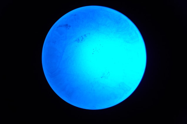 A sleek, glowing 3D wireframe globe slowly rotating against a deep midnight blue background.