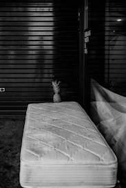 grayscale photography of ottoman beside mirror