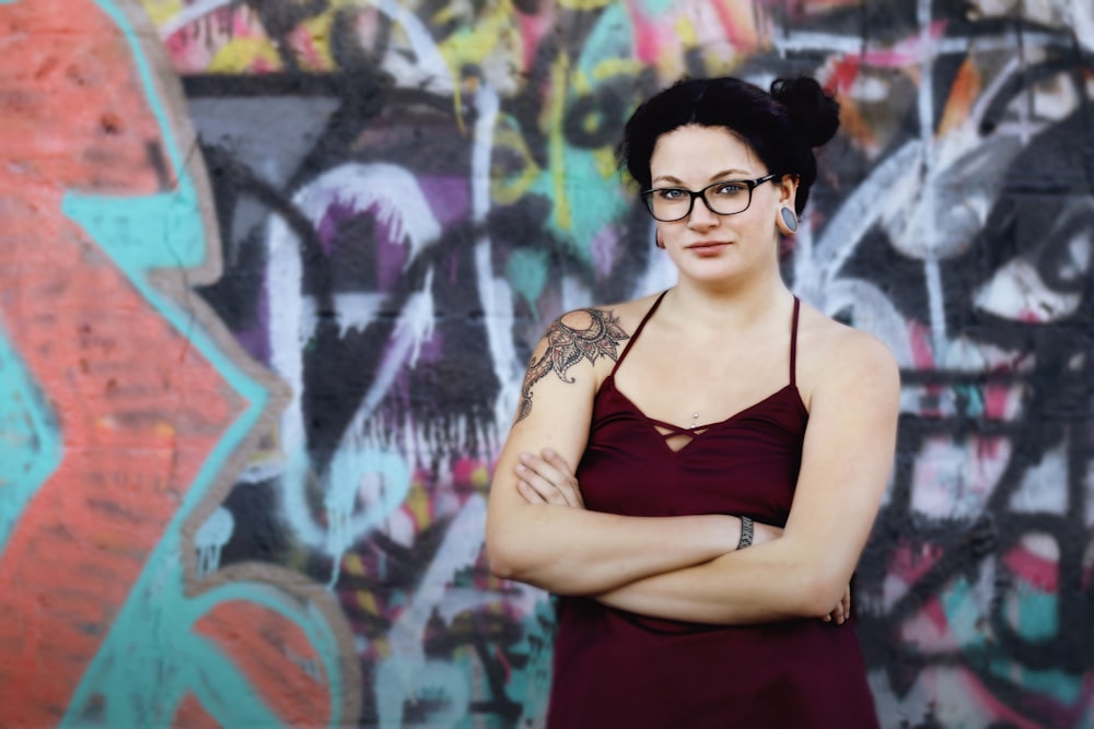 a woman standing in front of a wall covered in graffiti